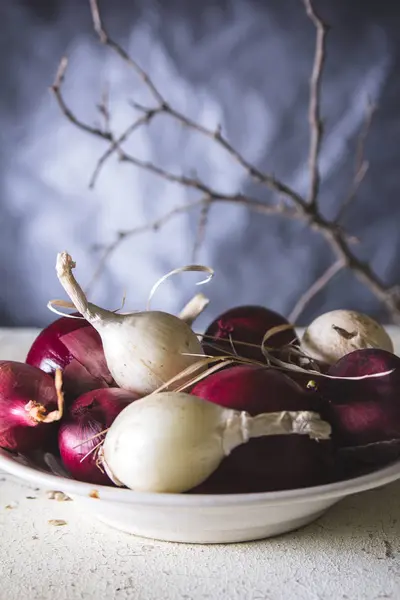 Ampoules à oignons rouges et blancs dans l'assiette sur une vieille table peinte en bois — Photo