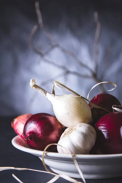 Rote und weiße Zwiebelzwiebeln im Teller auf schwarzem Tisch — Stockfoto