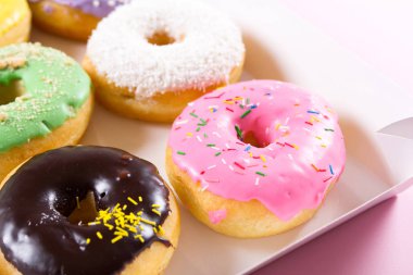 Çilek, chocklate ve diğer çörekler kağıt kutusunda pembe bir arka plan üzerinde