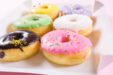 Çilek, chocklate ve diğer çörekler kağıt kutusunda pembe bir arka plan üzerinde