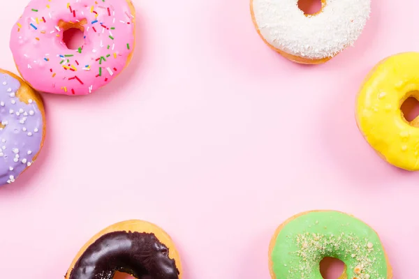 Pembe bir arka plan üzerinde renkli yuvarlak çörekler. Düz yatıyordu, en iyi görünümü.