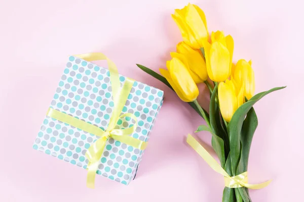 Bouquet de belles tulipes jaunes fraîches sur fond rose et boîte cadeau — Photo