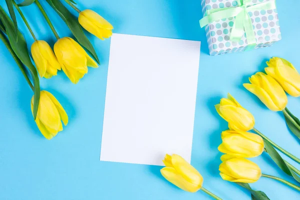 Bouquet de belles tulipes jaunes fraîches sur fond bleu et carte blanche pour le texte — Photo