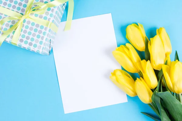 Bouquet de belles tulipes jaunes fraîches sur fond bleu et carte blanche pour le texte — Photo
