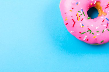 Mavi arka plan üzerinde pembe yuvarlak çörek. Düz yatıyordu, en iyi görünümü.