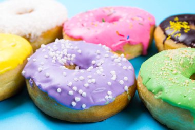 Mavi arka plan üzerinde renkli yuvarlak çörekler. Düz yatıyordu, en iyi görünümü.