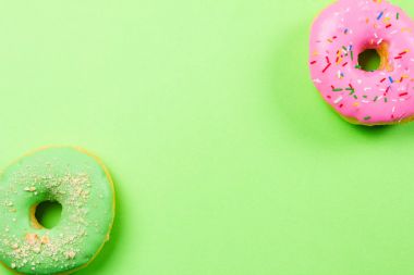 Yeşil arka plan üzerinde renkli yuvarlak çörekler. Düz yatıyordu, en iyi görünümü.