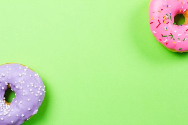 Yeşil arka plan üzerinde renkli yuvarlak çörekler. Düz yatıyordu, en iyi görünümü.