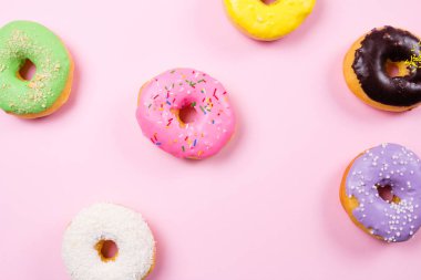 Pembe bir arka plan üzerinde renkli yuvarlak çörekler. Düz yatıyordu, en iyi görünümü.