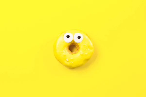 Rosquilla redonda con ojos sobre fondo amarillo. Piso tendido, vista superior . — Foto de Stock