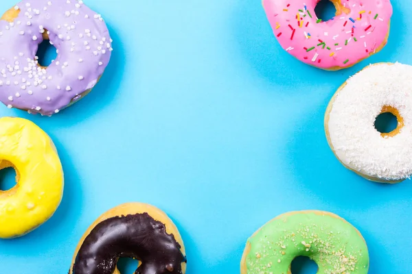 Mavi arka plan üzerinde renkli yuvarlak çörekler. Düz yatıyordu, en iyi görünümü.