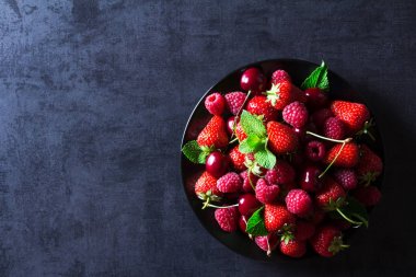 Taze kırmızı olgun meyveler siyah plaka üzerinde