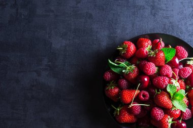 Taze kırmızı olgun meyveler siyah plaka üzerinde