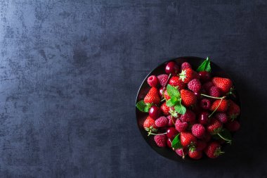 Taze kırmızı olgun meyveler siyah plaka üzerinde