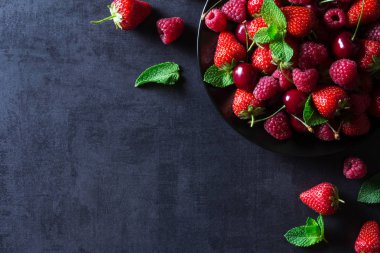 Taze kırmızı olgun meyveler siyah plaka üzerinde