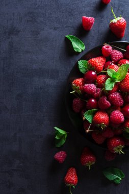 Taze kırmızı olgun meyveler siyah plaka üzerinde