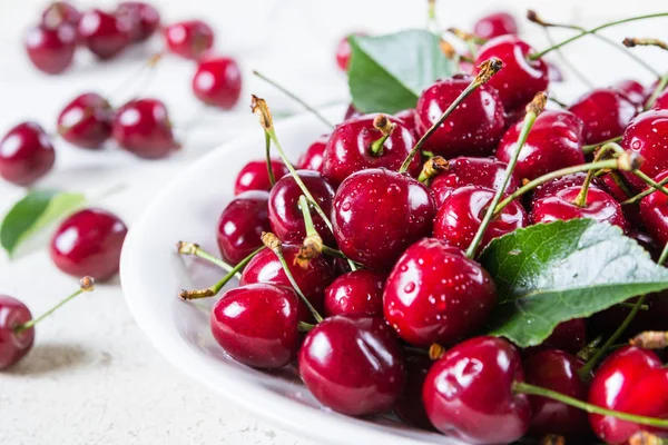 Свежие красные спелые вишни на белой тарелке — стоковое фото