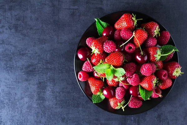 Taze kırmızı olgun meyveler siyah plaka üzerinde