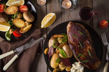 Biftek ve yanında fırında patates ve mantar tabağı.