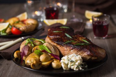 Biftek ve yanında fırında patates ve mantar tabağı.