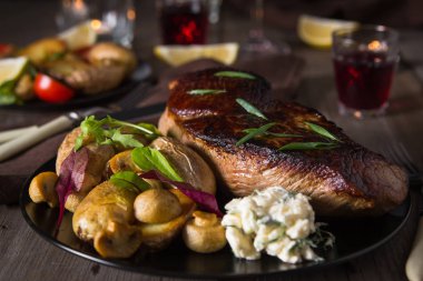 Biftek ve yanında fırında patates ve mantar tabağı.