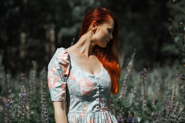 Retrato de uma linda menina ruiva em um campo de flores — Fotografia de Stock