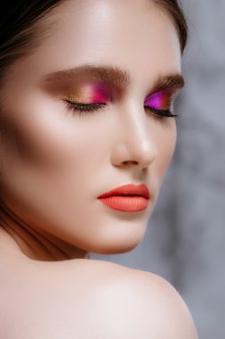 Mükemmel cilt ve yumuşak makyaj bir stüdyoda poz ile kız modeli. Esmer gri bir arka plan üzerinde. Güzel yüz.