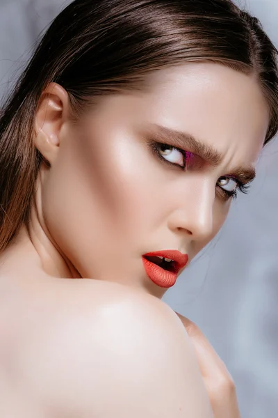 Meisje model met perfecte huid en zachte make-up poseren in een studio. De brunette op een grijze achtergrond. Mooi gezicht. — Stockfoto