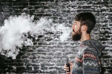 Elektronik sigara içen sakallı genç adam. Vaper hipster duman buharlaştırıcı..