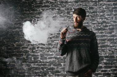 Elektronik sigara içen sakallı genç adam. Vaper hipster duman buharlaştırıcı..