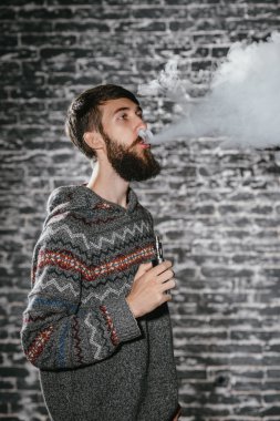 Elektronik sigara içen sakallı genç adam. Vaper hipster duman buharlaştırıcı..