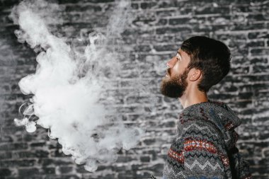 Elektronik sigara içen sakallı genç adam. Vaper hipster duman buharlaştırıcı..