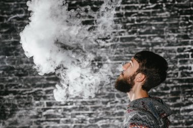 Elektronik sigara içen sakallı genç adam. Vaper hipster duman buharlaştırıcı..