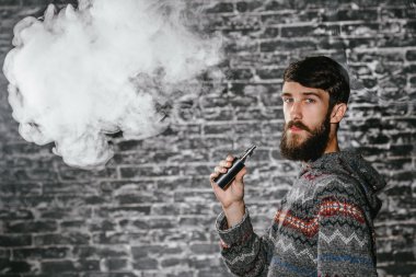 Elektronik sigara içen sakallı genç adam. Vaper hipster duman buharlaştırıcı..