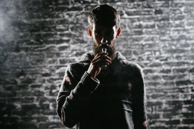 Elektronik sigara içen sakallı genç adam. Vaper hipster duman buharlaştırıcı..
