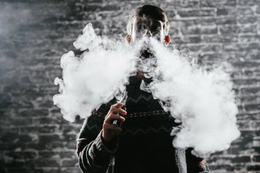 Elektronik sigara içen sakallı genç adam. Vaper hipster duman buharlaştırıcı..