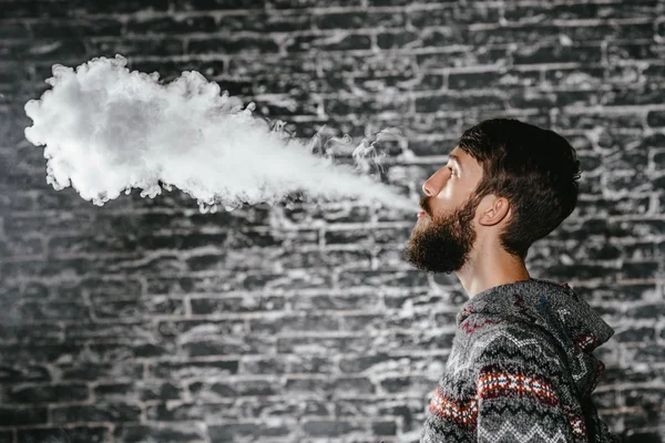 Elektronik sigara içen sakallı genç adam. Vaper hipster duman buharlaştırıcı..