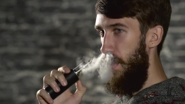 Young man with beard vaping an electronic cigarette. Vaper hipster smoke vaporizer in slow motion — Stock Video