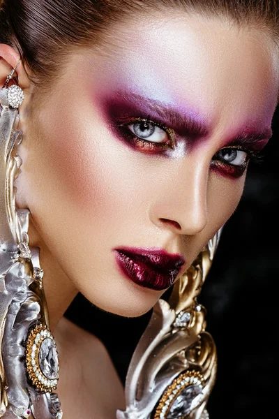 Brunette vrouw in lange oorbellen. middelbare school model met creatieve make-up — Stockfoto