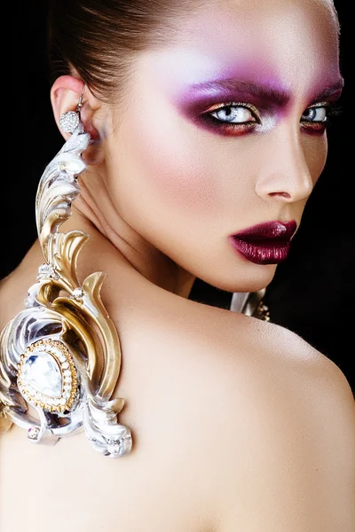 Brunette vrouw in lange oorbellen. middelbare school model met creatieve make-up — Stockfoto
