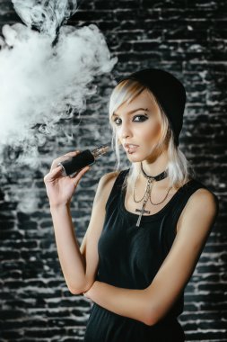 Seksi goth kız koyu arka plan üzerinde elektronik sigara içiyor. Model vaper vaping bir Buharlaştırıcı stüdyo.