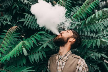 Sakal vaping elektronik sigara açık olan genç adam. hipster duman Buharlaştırıcı.