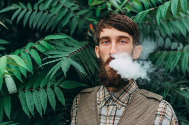 Sakal vaping elektronik sigara açık olan genç adam. hipster duman Buharlaştırıcı.