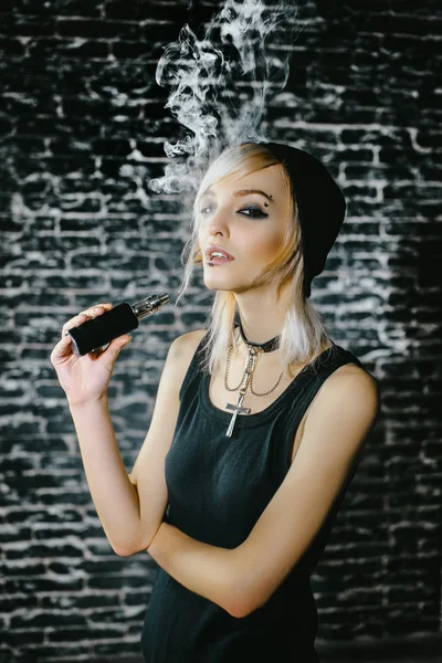 Sexy chica gótica fuma cigarrillo electrónico sobre fondo oscuro. El modelo vaper vapeando un vaporizador en el estudio . — Foto de Stock