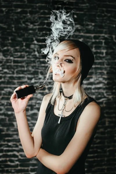 Menina gótica sexy fuma cigarro eletrônico no fundo escuro. O modelo vaper vaporizando um vaporizador no estúdio . — Fotografia de Stock