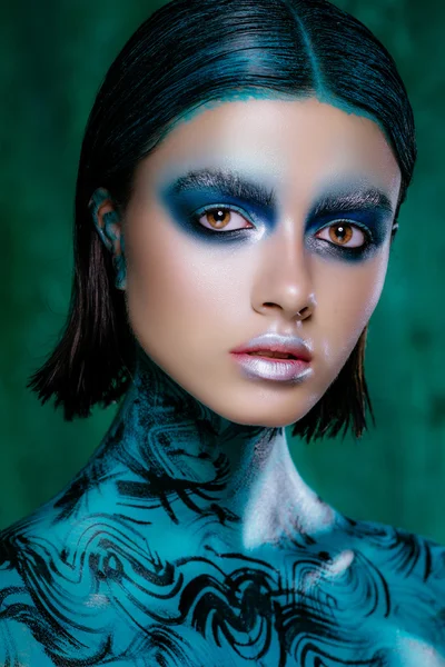 Art make-up élénk színek. Gyönyörű barna lány pózol a stúdióban, a türkiz háttér rövid haj. Ragyogó bőr — Stock Fotó