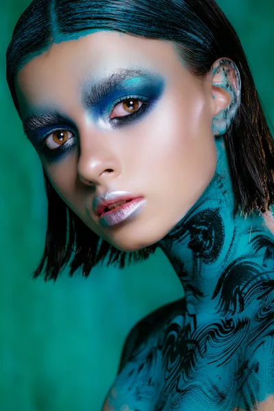 Maquillage d'art en couleurs vives. Belle fille brune en cheveux courts posant en studio sur un fond turquoise. Peau éclatante — Photo