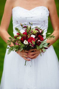 kırmızı bir buket tutan gelin. düğün çiçekleri. yumuşak odak.