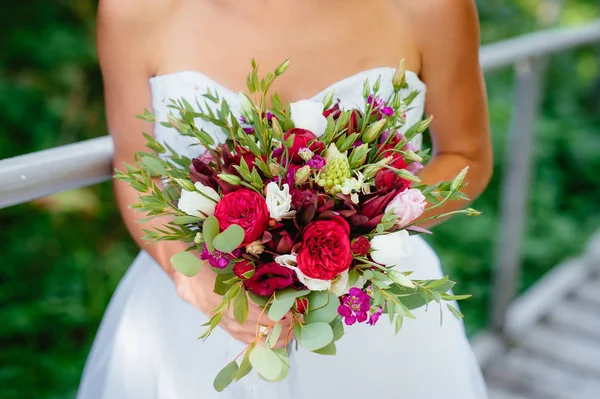 A noiva segurando um buquê vermelho. flores do casamento. foco suave . — Fotografia de Stock