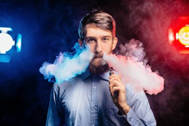 Genç adam bir sakal vaping ile ve Buhar bulutu serbest bırakır. hipster vaper duman Buharlaştırıcı.